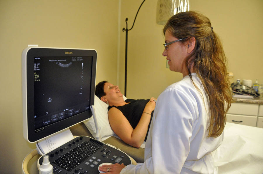 Pregnancy Health Center Nurse Manager Brenda Droege demonstrates an ultrasound on PHC Executive Director Heather Mitchell in the center's new medical clinic.